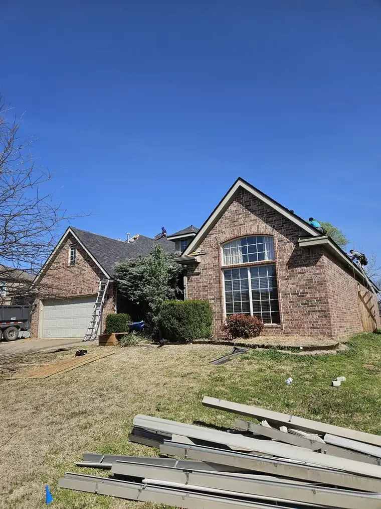 Two-story brick job with trim and gutter stock staged for the finish — Bartlesville Roofing & Gutters, Bartlesville OK